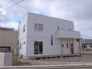 遠くに船が見える丘に建つ家